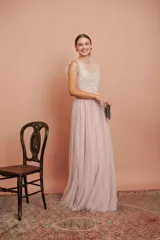 Vestido largo de tul plumetí en color rosa suave, con detalles de encaje bordado en el torso y volados en los hombros.