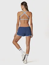 Short deportivo 2 en 1 color azul con detalles en celeste, que incluye calza interior incorporada. Presenta una cintura ancha de tiro alto en color tostado, con diseño de bordes redondeados y costuras a contratono.