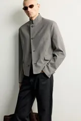 Blazer cropped de corte ajustado con estampado de cuadros, cuello mao y manga larga. Cuenta con bolsillos con solapa en la cadera y cierre frontal de botones.