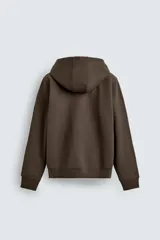 Sudadera con capucha y cierre frontal de cremallera bidireccional, confeccionada en tejido de algodón pesado con interior de rizo. Presenta corte relajado, mangas largas con puños acanalados, bajo elástico y bolsillos frontales tipo canguro.