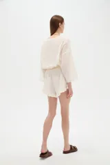 Short de algodón con diseño de broderie, tiro alto, calce holgado y detalle de volados en el ruedo.