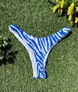 Conjunto de bikini con estampado de cebra en tonos azul y blanco. El corpiño es de un hombro y la bombacha es colaless.