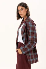 Blazer de corte oversize con estampado de cuadros en tonos azul, bordó y marrón. Presenta solapas clásicas, bolsillos con solapa en el frente y cierre frontal con botones.