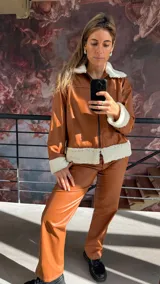 Campera marrón de cuero sintético con cuello, puños y ruedo de corderito blanco.