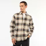 Camisa de manga larga con diseño de cuadros en tonos beige, negro y gris. Presenta cuello clásico, cierre frontal con botones y puños abotonados.