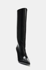 Bota de caña alta con acabado efecto acharolado, diseño de punta fina y tacón alto fino.