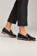 Mocasines negros de cuero vacuno con detalles texturizados en la capellada, suela plana y vira en contraste color madera.