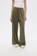 Pantalon deportivo de corte ancho y tiro alto, color verde oliva, con cintura elástica y una línea vertical blanca lateral en cada pierna.