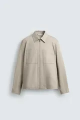 Sobrecamisa de hombre color beige claro, de corte relajado, con cuello solapa, cierre frontal de cremallera, bolsillos de plastrón en el pecho y bolsillos de vivo en la cadera.
