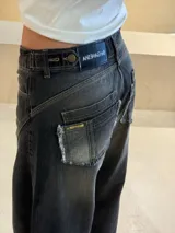 Pantalón de jean recto color gris oscuro, con efecto desgastado, recortes 360 y ajuste en cintura con presillas. Tiene tiro medio y detalles de bolsillos traseros con parches deshilachados.
