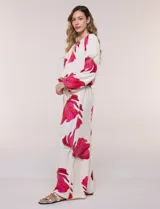 Conjunto de dos piezas de crep compuesto por una blusa holgada con escote en V y mangas largas abullonadas, y un pantalón palazzo tiro alto con pretina elástica. Presenta un estampado floral en tonos rosados sobre base blanca.