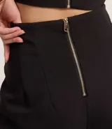 Pantalón de vestir negro, de corte palazzo, sin cintura, con pliegues y cierre trasero.