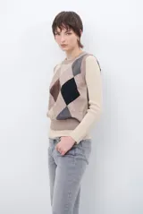 Chaleco de punto con diseño de rombos en tonos beige, marrón y gris. Presenta cuello redondo y corte ajustado a la cintura.