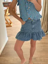 Minifalda de denim con volados en el borde inferior y bolsillos delanteros.