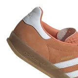 Championes adidas modelo Gazelle, confeccionados en gamuza color naranja con las icónicas tres tiras laterales en blanco. Presentan suela de goma color caramelo y detalle de talón en blanco.