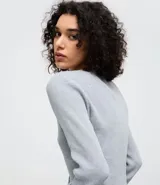 Cardigan de punto texturizado color rosado, con escote en V, cierre frontal por botones, mangas largas y acabado con volados sutiles en el ruedo y los puños.