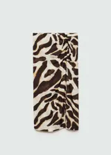 Falda midi de viscosa con estampado animal print en tonos marrones y crema. Presenta un diseño recto con detalle drapeado lateral y una abertura pronunciada en la pierna. Cuenta con cierre de cremallera invisible en la parte posterior.
