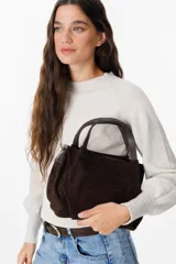 Bolso de mano tipo tote pequeño, confeccionado en cuero gamuzado color chocolate, con asas cortas de cuero liso y cierre superior.