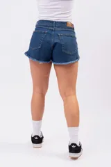 Short de denim azul índigo con tiro medio-alto, bolsillos clásicos y terminación desmechada en las piernas.