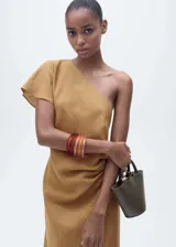Vestido midi de lino color tostado, con diseño asimétrico de un solo hombro, manga corta y cintura drapeada con abertura lateral en el bajo.