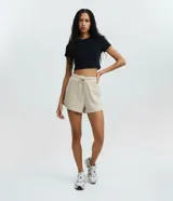 Short de microfibra color beige, de tiro medio con cintura elástica y cordón de ajuste. Cuenta con bolsillos laterales y detalles de ribete en los bordes.