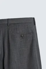 Pantalón de traje regular fit color gris oscuro, confeccionado en tejido con lana, con bolsillos frontales y bolsillos traseros de doble vivo con botón. Cierre frontal con cremallera y botón.