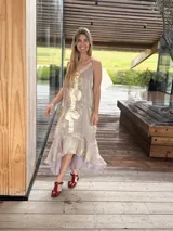 Vestido midi lila con acabado brillante y tirantes finos regulables, diseño con aplicaciones de cuero dorado en el centro y bajo asimétrico con volados.