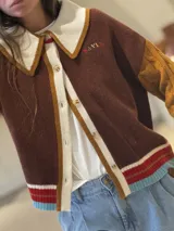 Cardigan de punto con diseño color block, cuello estilo polo en color rosado con borde rojo, cierre frontal con botones, manga derecha en verde oliva y manga izquierda en rojo, con puños y ruedo acanalados a rayas multicolor.