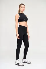 Top deportivo negro con escote alto, abertura en el centro del pecho y ribete blanco en sisas y cuello.