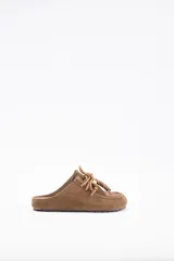 Zueco de cuero vacuno color marrón, con diseño de puntera reforzada y cordones decorativos con cuentas de madera en el empeine.