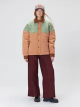 Campera acolchada de diseño colorblock, con el pecho y hombros en tono bordó y el cuerpo y mangas en color beige. Presenta cuello camisero y puños de pana negra, cierre frontal oculto con botones a presión y costuras pespuntadas en patrón cuadriculado.