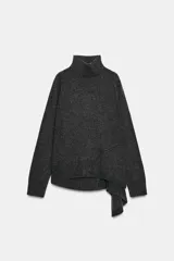 Jersey de lana con cuello subido, manga larga y bajo asimétrico con detalle de nudo lateral. Presenta acabados en rib en cuello, puños y ruedo.