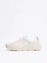 Zapatillas deportivas Tommy Hilfiger de corte bajo, color blanco con detalles en celeste y plateado. Presentan paneles de malla y superposiciones de gamuza, con el monograma TH en la lengüeta y el lateral.