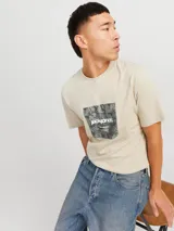 Remera color arena de manga corta y cuello redondo, con estampado cuadrado en el frente con diseño de camuflaje y logo de la marca.