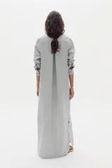 Vestido largo camisero de lino a rayas celestes y blancas, con cuello camisero, mangas largas, bolsillo aplicado en el pecho y cierre frontal con botones.
