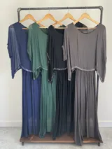 Vestido largo de seda italiana en color gris oscuro, con falda larga lisa, forro y cintura elastizada. Posee una sobrecapa con detalles de paillettes en los bordes de las mangas y la cintura.