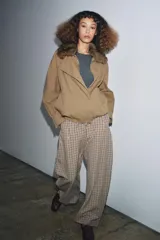 Chaqueta tipo bomber de color beige, con cuello solapa y aplicación extraíble de pelo sintético. Presenta cierre frontal con botones a presión ocultos, bolsillos delanteros y bajo con elástico.