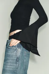 Camiseta de cuello redondo y manga larga, confeccionada en tejido rib con mezcla de lyocell. Presenta un diseño ajustado con terminación de volantes en los puños y bajo recto.