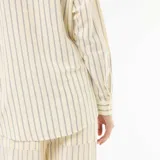 Camisa de lino mezclado color amarillo con patrón de rayas verticales finas en tono azul marino. Presenta cuello camisero, cierre frontal con botones y mangas largas.