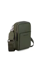 Bandolera pequeña de diseño compacto en color mostaza, confeccionada en material sintético con textura granulada. Presenta un bolsillo frontal con el logo de la marca impreso, cierre superior y correa ancha ajustable y desmontable.