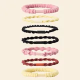 Pack de siete gomas para el pelo con diferentes texturas y colores, incluyendo tonos rosa, amarillo, negro y bordó. Cada elástico cuenta con un cierre central a tono.