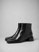 Bota de cuero color negro, de caña corta con punta cuadrada y taco bloque bajo.