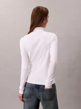 Top de manga larga Calvin Klein color blanco, confeccionado en punto fino de algodón y licra. Presenta cuello tortuga, ajuste ceñido al cuerpo y un pequeño parche con el monograma de la marca en el pecho.