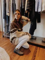 Sweater artesanal tejido a mano en lana merino, con diseño bicolor en marrón y tostado. Presenta un canesú texturado con trenzas y pequeños bodoques, cuello redondo y un patrón geométrico jacquard en mangas y cuerpo.