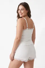 Conjunto de pijama de dos piezas de tejido rib color blanco, compuesto por una musculosa de tirantes finos con detalle de encaje en el escote y un short con detalles de encaje en el ruedo.