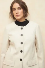 Tapado largo color crema, de paño, con cuello a la base y botones redondos veteados.