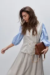 Chaleco de calce entallado color beige, de estilo cruzado con doble botonadura y escote redondo.
