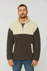 Buzo de sherpa con diseño color block, combinando paneles en color crema y gris oscuro. Presenta cuello alto con cierre frontal parcial y bolsillos laterales con ribete en color crema.