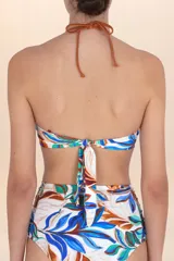 Top de bikini estilo halter con frunces centrales y ribete color terracota. Presenta un estampado botánico en tonos blanco, azul, verde y marrón. Los breteles son ajustables mediante lazo en la nuca.