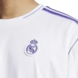 Camiseta de fútbol Adidas del Real Madrid, inspirada en los modelos de los años 80. Diseño blanco con detalles en violeta, logo de Adidas y escudo del club bordados. Corte holgado.